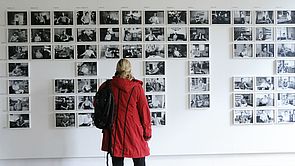 Eine Frau betrachtet Fotografien an der Wand.