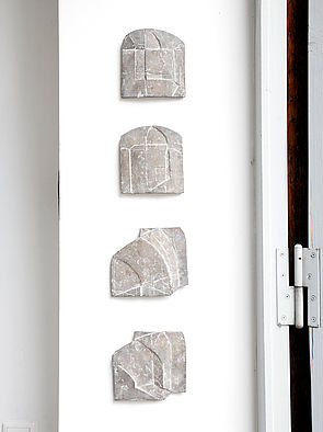 Vier Reliefs hängen untereinander auf weißem Untergrund.