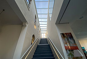 Links und rechts eine weiße Wand, dazwischen eine passgenaue Treppe. Darüber ein Glasdach.