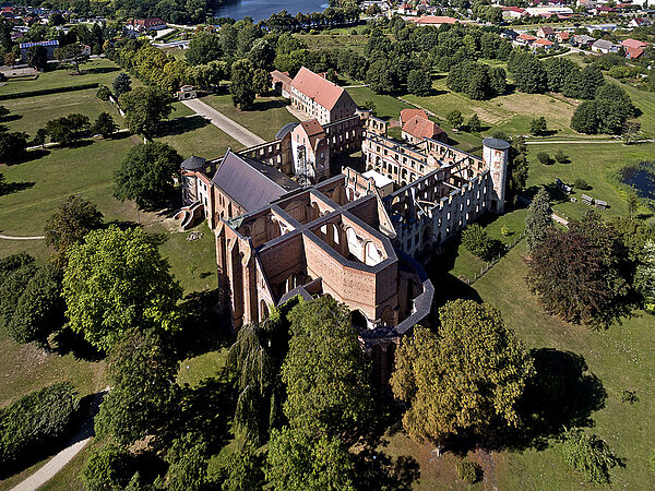 Ein Luftbild von der Kloster- und Schlossanlage. Die Gemäuer sind umgeben von vielen Bäumen und Wiesen.