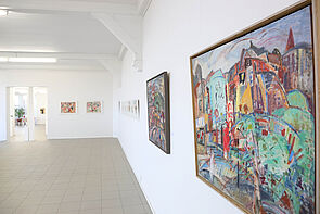 Blick in den Ausstellungsraum. Zu sehen sind farbige Bilder.