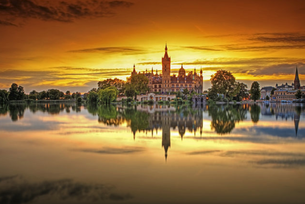 Das Schweriner Schloss spiegelt sich bei Sonnenuntergang im Schweriner See.