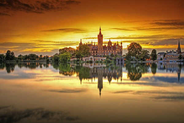 Das Schweriner Schloss spiegelt sich bei Sonnenuntergang im Schweriner See.