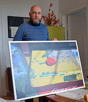 Heiko Krause hält eine große Fotografie fest.