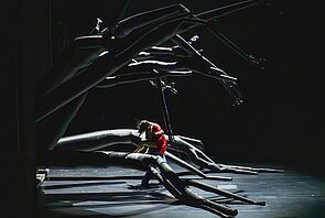 Eine Frau im roten Kleid auf einer dunklen Bühne.