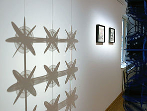 Ein Ausstellungsraum. An der Wand eine Licht-Schatten-Installation von Stine Albrecht.