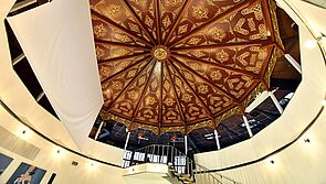 Die Decke gleicht einem runden, rot-goldenen Schmuckornament. 