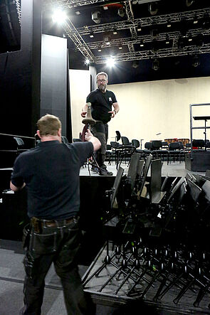 Instrumente, Stühle etc. Zwei Männer packen alles ein.