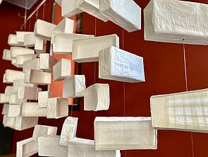 Detailaufnahme auf kleine, weiße, offene Schachteln, die von der Decke hängen. 