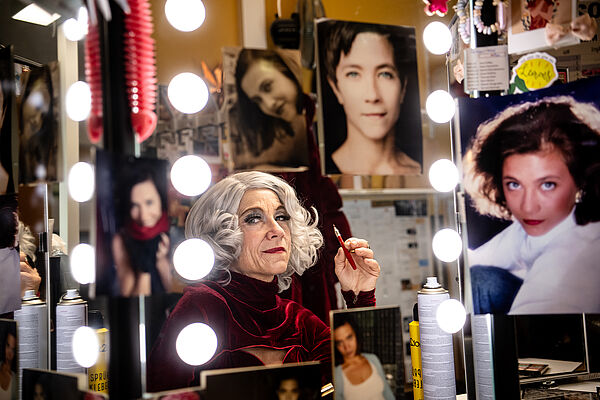 Eine Frau als ältere Sängerin geschminkt.