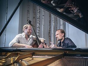 Zwei Männer sitzen an einem Konzertflügel mit aufgeklapptem Klangkörper.