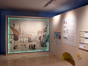 Eine Zeichnung von Greifswald hängt an der Wand und wird am Rand grün beleuchtet.