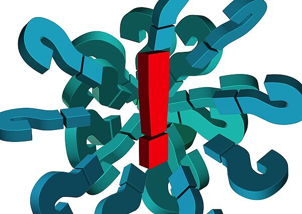 Auf weißem Hintergrund liegen viele dunkle Fragezeichen. In der Mitte befindet sich ein rotes Ausrufezeichen.