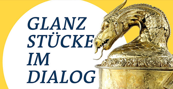 Das Plakat zur Ausstellung. Rechts befindet sich der Ausschnitt eines goldenen Pokals mit einem Deckel in Tieroptik. Links steht „Glanzstücke im Dialog“. 