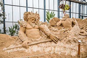 Ein Meeresgott. Die Figur ist aus Sand. Die Figur ist größer als ein Mensch.