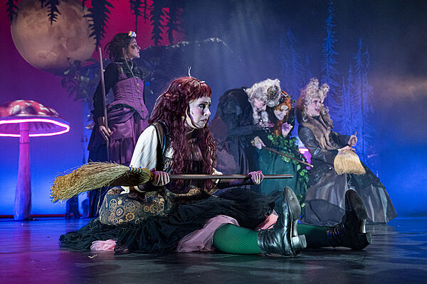 Eine Hexe mit Besen im Vordergrund, dahinter weitere Hexen