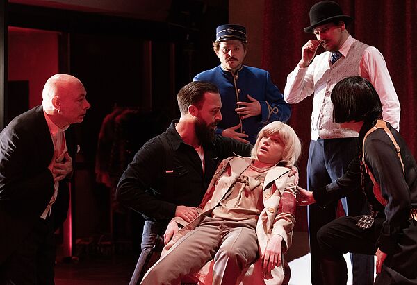 Schauspieler auf der Bühne. Einer beugt sich über eine zusammengesackte Person.