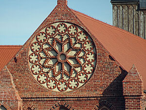 Rundes Schmuckornament im Blumendesign an einer Backsteinwand.