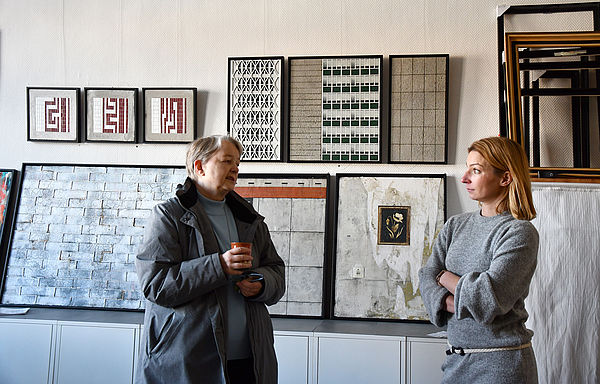 Dr. Dr. Merete Cobarg von der Kunstsammlung Neubrandenburg vor Bildern von Juli Schupa. Die Künstlerin steht am rechten Bildrand.