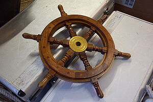 Auf zwei silbernen Koffern liegt ein Steuerrad.