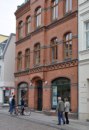 Das Caspar-David-Friedrich-Zentrum ist ein dreigeschossiges Backsteinhaus. Auf dem Fußweg davor gehen Leute.