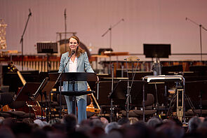 Eine Frau steht auf der Bühne und hält eine Rede.