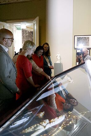 Menschen stehen vor einer Vitrine im Museum.