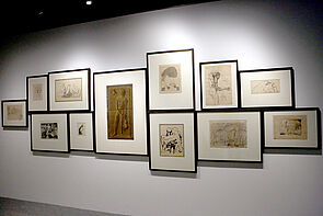 Eine Auswahl von Bildern hängt an der Wand.