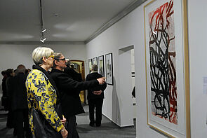 Besucherinnen und Besucher stehen vor einem großen Bild an der Wand. 