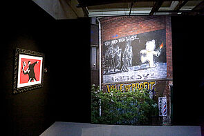 Ein vermummter Mann wirft Blumen. Ein berühmtes Banksy-Bild.