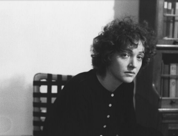 Ein schwarz-weiß-Porträt zeigt eine Frau, die auf einem Stuhl sitzt und in die Kamera schaut.