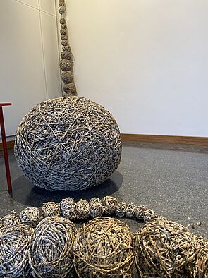 Große und kleine Knäuel liegen aneinandergereiht auf dem Boden. 