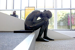 Eine Skulptur. Sie zeigt einen Jungen, der kniet.