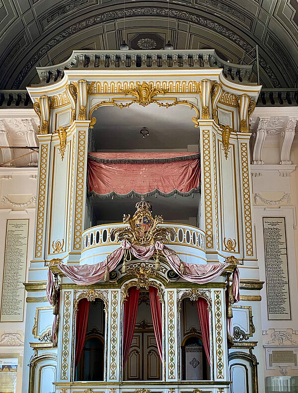 Eine Empore. Im Erdgeschoss befindet sich eine Loge. Darüber befinden sich noch drei Etagen. Empore ist prunkvoll verziert.