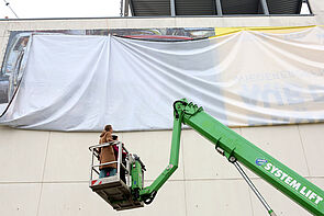 Ein riesiges Plakat ist verhüllt.