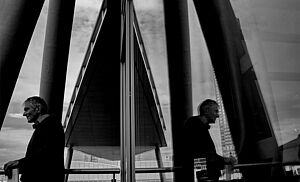 Ein Mann spiegelt sich in den Scheiben eines Gebäudes. 