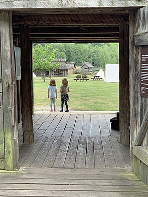 Zwei Mädchen hinter dem Eingang und blicken auf das alte Slawendorf.