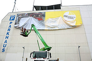 Langsam entrollt sich das Plakat.