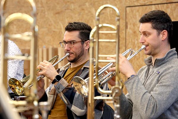 Zwei Musiker proben mit der Trompete.