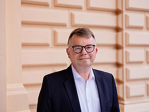 Ein Mann. Der Mann steht vor dem Theater.