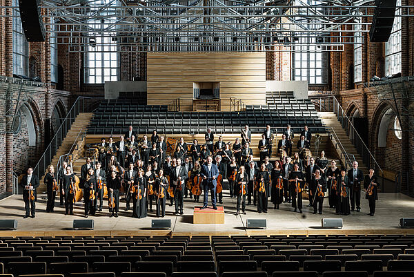 Ein Orchester steht auf der Bühne.