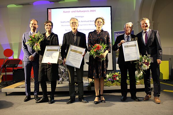 Sechs Personen stehen für ein Foto auf der Bühne.