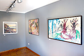 Drei Bilder hängen an der Wand der Galerie.
