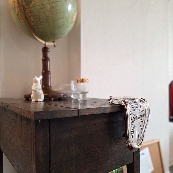 Eine Uhr zerfließt auf einem Tisch.