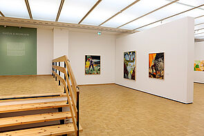 Blick in die Ausstellung. Zu sehen sind drei Gemälde.