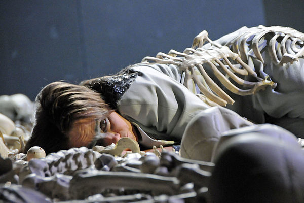 Brunhild liegt auf der Bühne, umgeben von Knochen und Skeletten. 