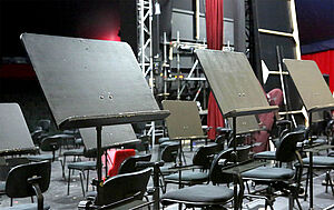 Drei leere Orchesterpulte. 