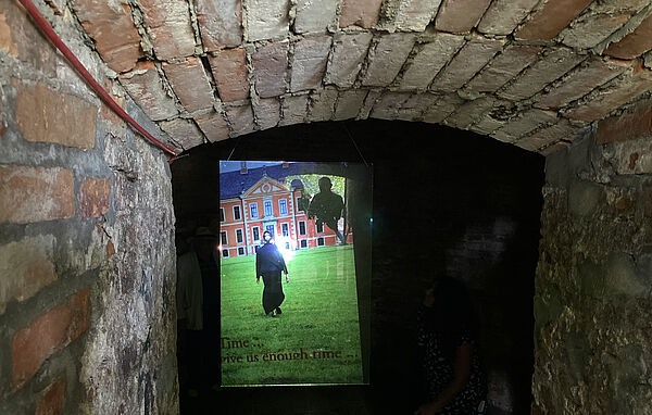 Ein Keller aus Ziegelsteinen. Darin läuft ein Video.