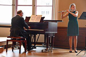 Julia Jeschke spielt Querflöte. Jörg Simon sitzt am Klavier.