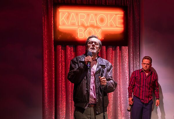 Ein Mann singt Karaoke auf einer Bühne.